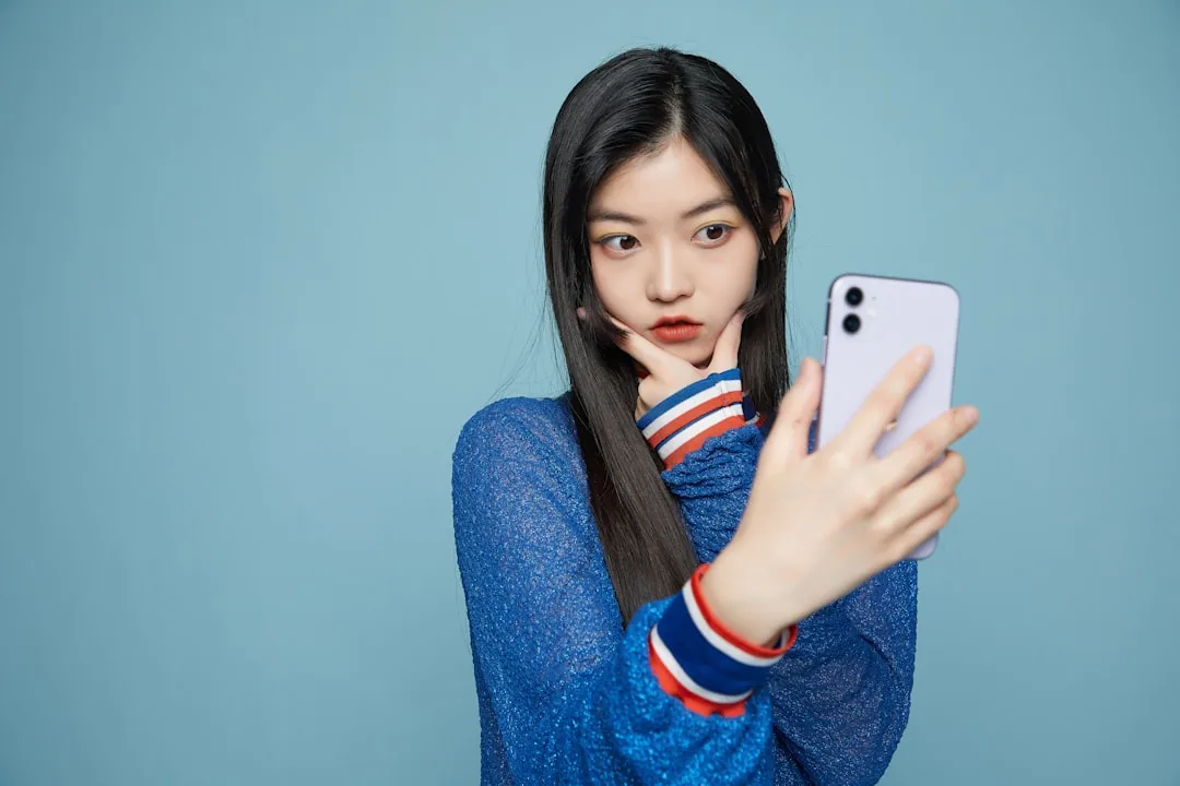 스마트폰으로 자신의 얼굴 사진을 확인하며 헤어스타일 앱을 사용하는 모습을 담은 이미지